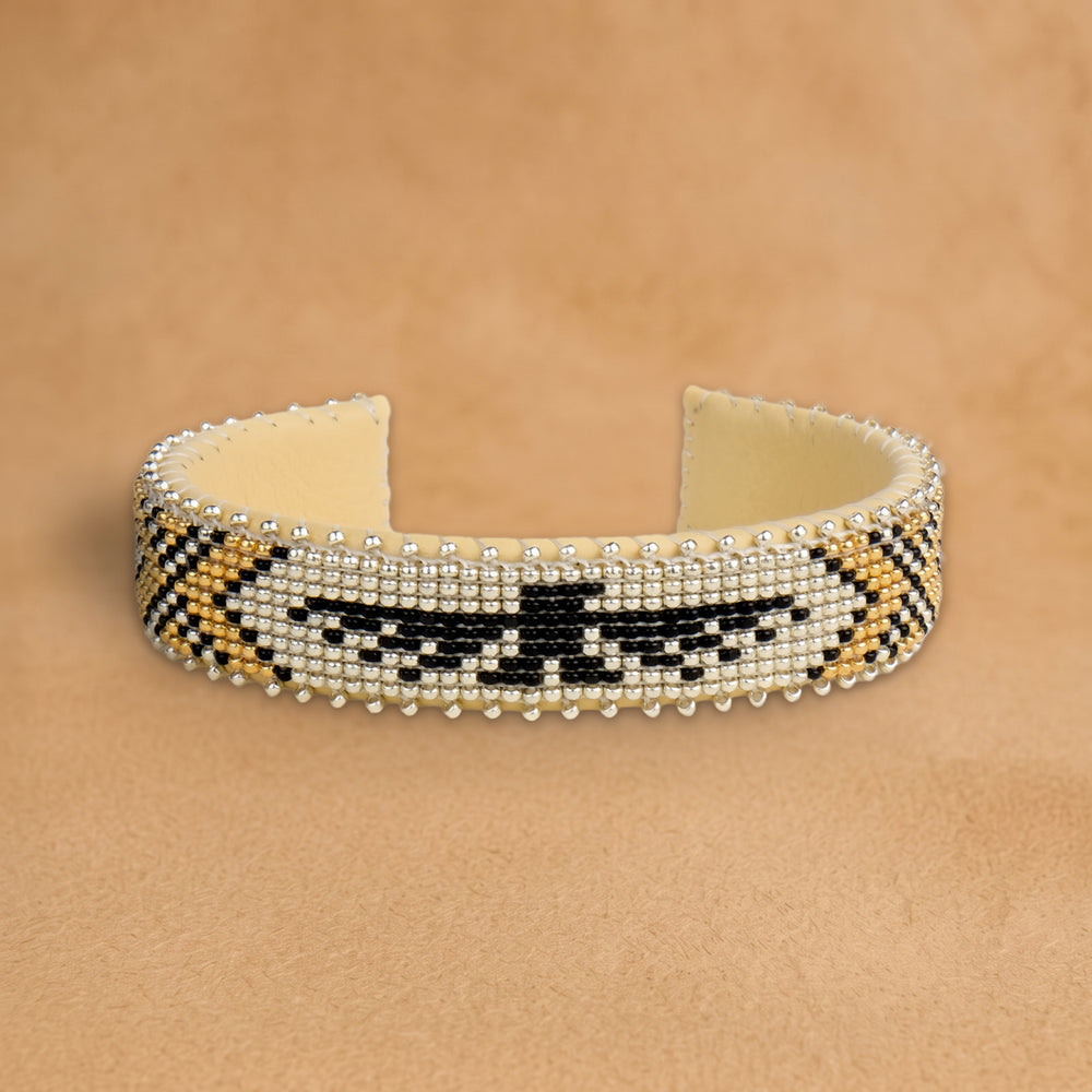 Tallulah Small beaded cuff, silver with a black thunderbird and gold chevrons, handloomed by Navajo artisans in New Mexico